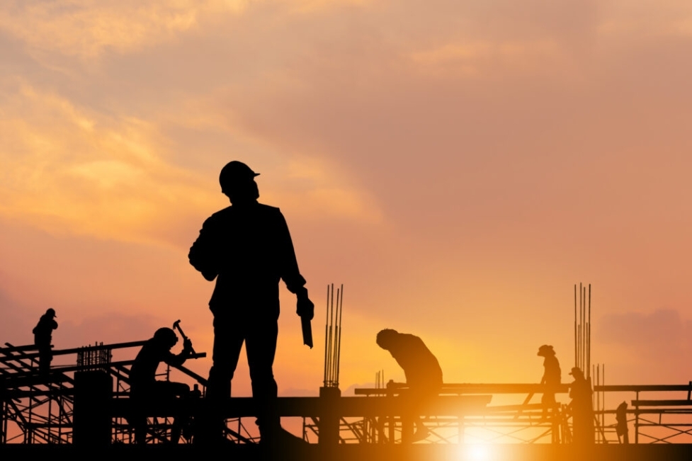 Construction workers on top of scaffolding during the sunset.